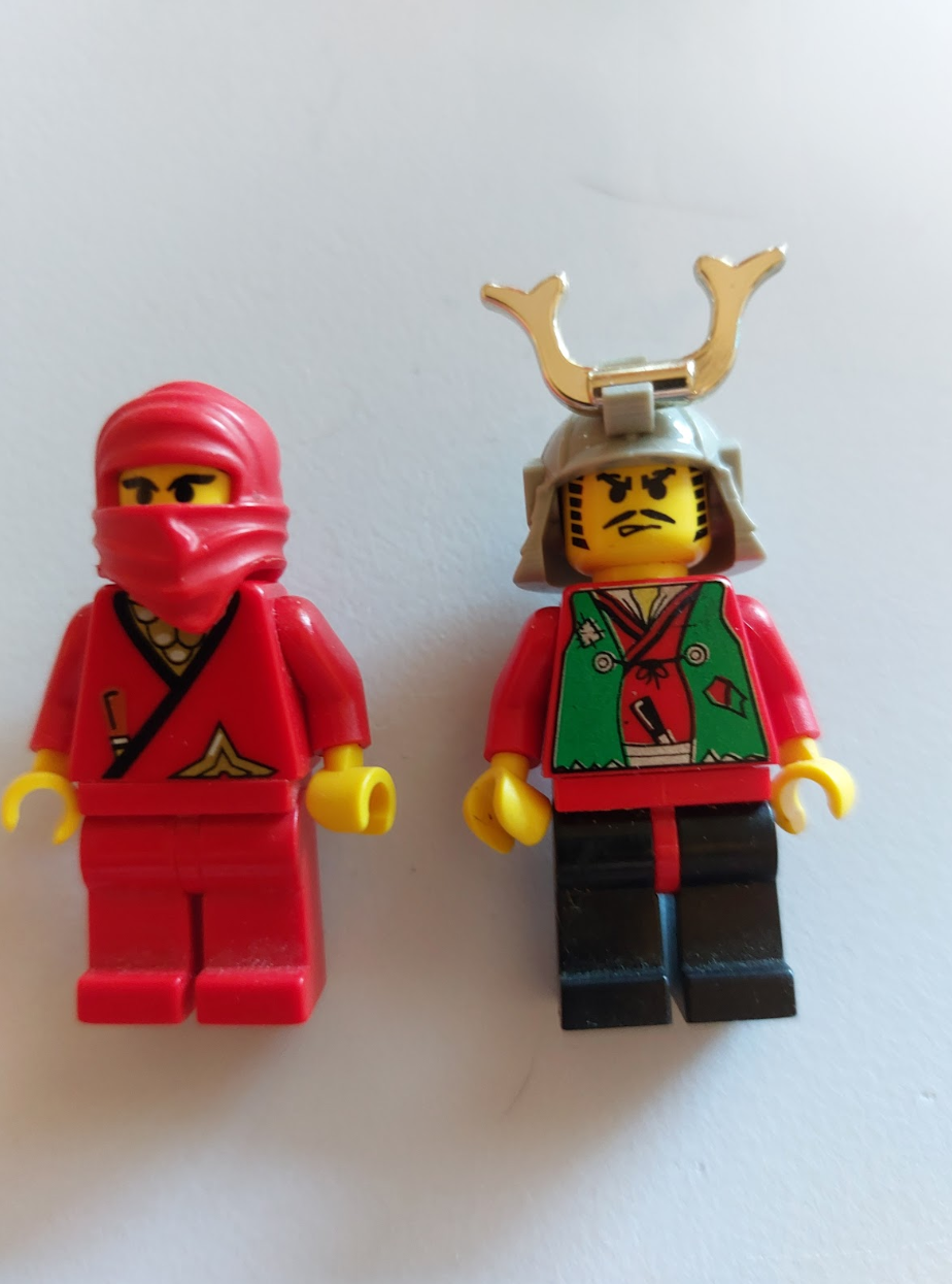 Two lego mini-figs laying side by side from the samurai and ninja sets